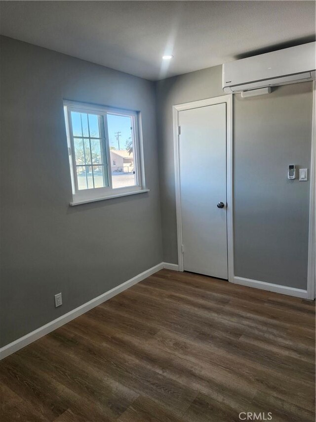 unfurnished bedroom featuring dark hardwood / wood-style flooring, a closet, and a wall mounted air conditioner