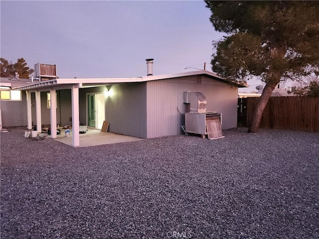 back house at dusk featuring a patio area