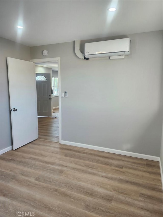 unfurnished room with light hardwood / wood-style floors and a wall mounted air conditioner