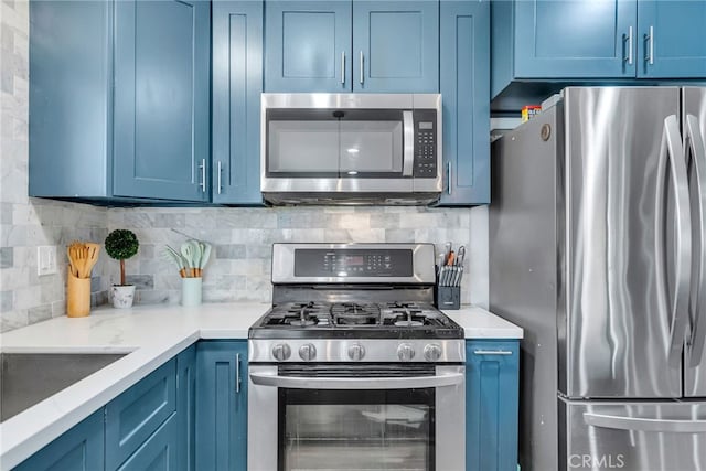 kitchen with appliances with stainless steel finishes, backsplash, blue cabinetry, and light stone countertops