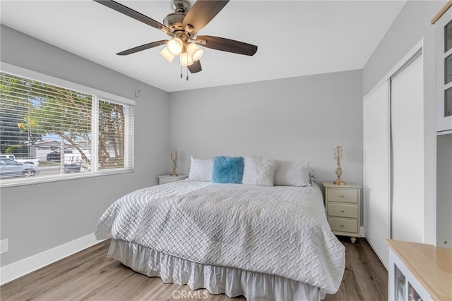 bedroom with ceiling fan, wood-type flooring, and a closet