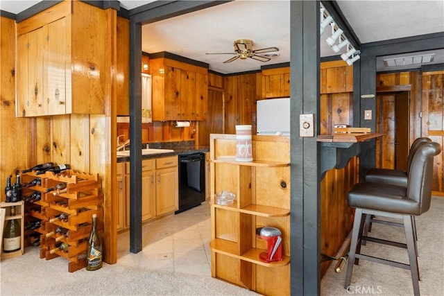 kitchen featuring ceiling fan, a kitchen breakfast bar, black dishwasher, and wood walls