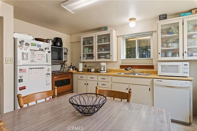 kitchen with white cabinets, sink, and white appliances