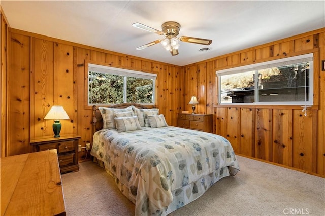 carpeted bedroom featuring ceiling fan and wood walls