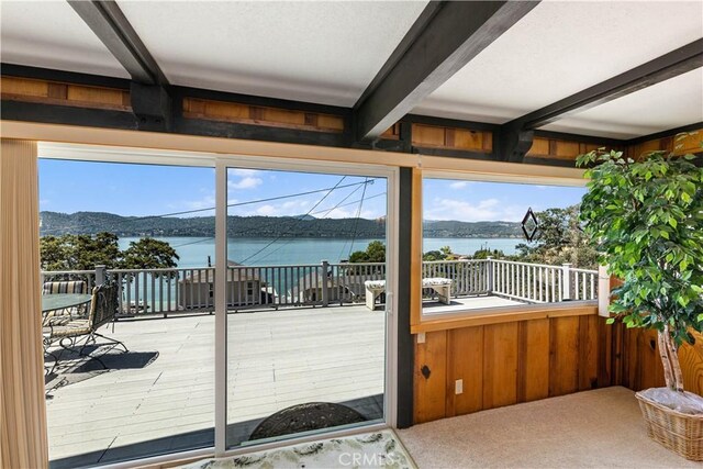 doorway with beam ceiling, light colored carpet, and a water and mountain view