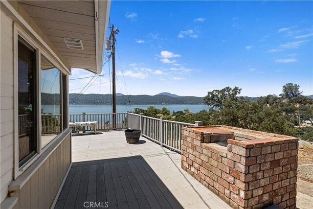 wooden deck with a water and mountain view