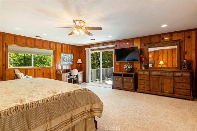 carpeted bedroom with ceiling fan, wood walls, and access to outside