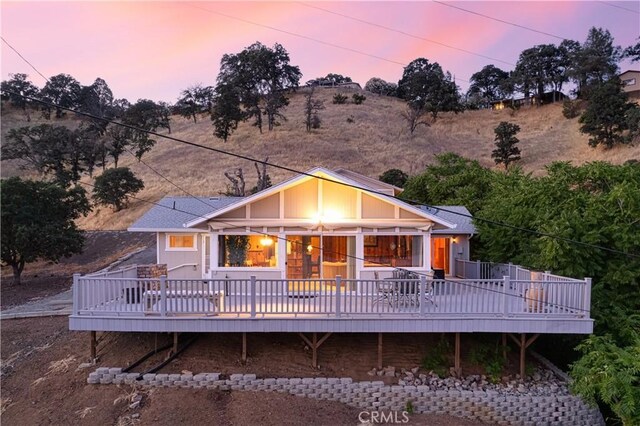 back house at dusk featuring a wooden deck