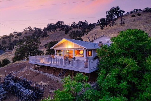 back house at dusk featuring a deck