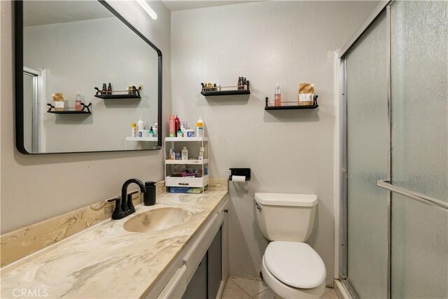 bathroom featuring a shower with shower door, tile patterned floors, toilet, and vanity