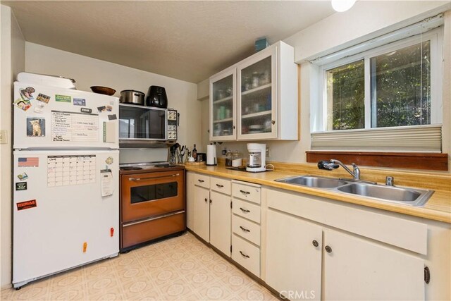 kitchen featuring white cabinetry, sink, electric stove, and white fridge