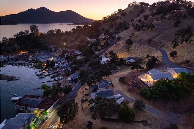 aerial view at dusk featuring a water and mountain view