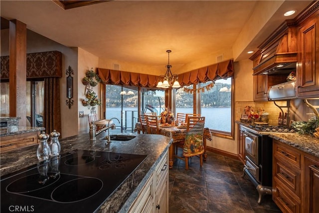 kitchen featuring a wealth of natural light, black electric stovetop, dark stone counters, stainless steel gas stove, and a water view