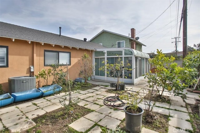 rear view of property with cooling unit, a patio area, and a sunroom