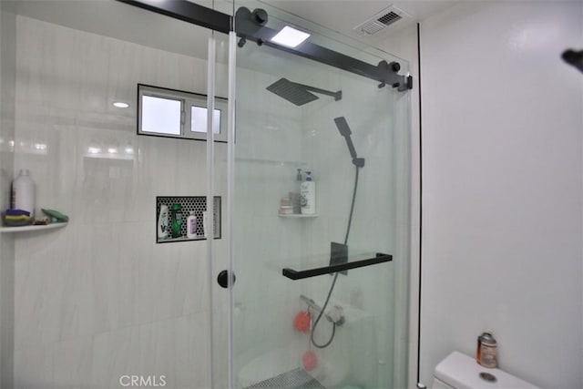 bathroom with a shower with shower door and toilet