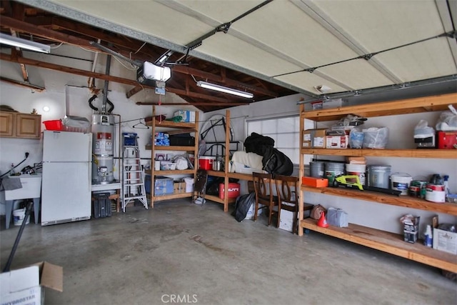 garage featuring sink, water heater, a garage door opener, and white refrigerator