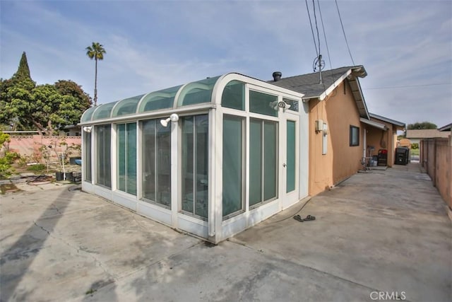 view of side of property featuring a sunroom and a patio