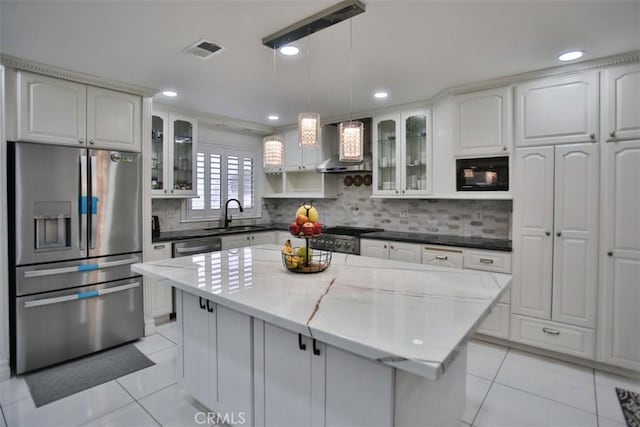 kitchen featuring white cabinets, appliances with stainless steel finishes, a center island, and wall chimney exhaust hood