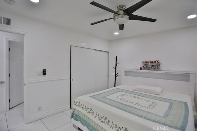 tiled bedroom with ceiling fan and a closet