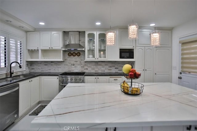 kitchen with decorative light fixtures, wall chimney exhaust hood, and dark stone countertops