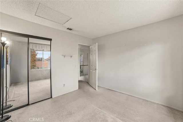 unfurnished bedroom with a textured ceiling, a closet, and light carpet