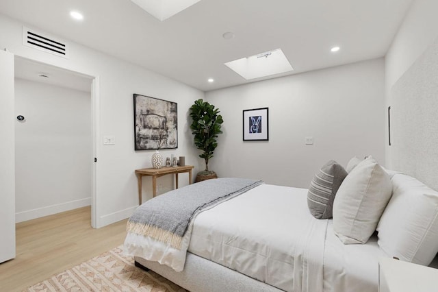 bedroom with light wood-type flooring and a skylight