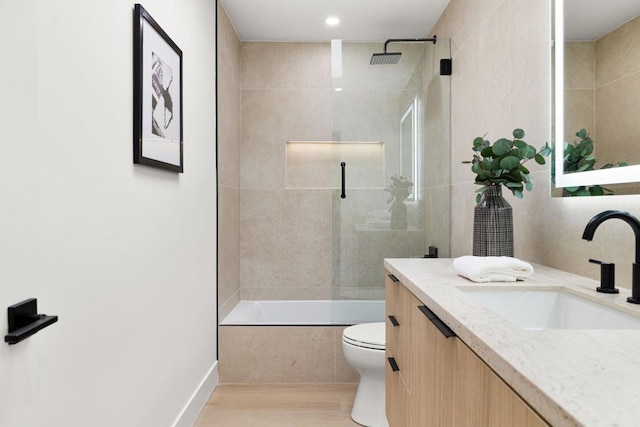 full bathroom featuring bath / shower combo with glass door, toilet, vanity, and hardwood / wood-style floors