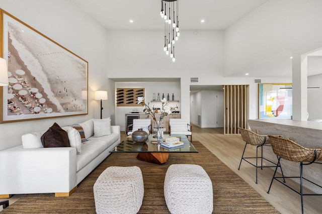 living room with wine cooler, a towering ceiling, and hardwood / wood-style flooring