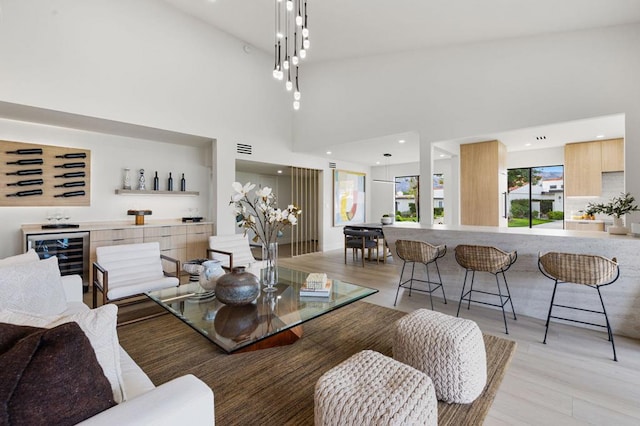 dining room with light hardwood / wood-style flooring, indoor bar, wine cooler, and a high ceiling