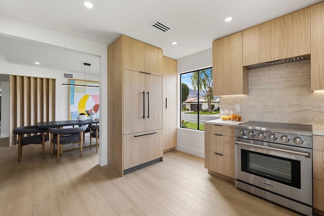 kitchen featuring light brown cabinetry, decorative backsplash, and high end appliances