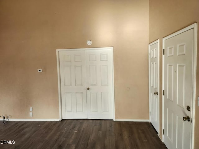 unfurnished bedroom featuring a high ceiling and dark hardwood / wood-style flooring