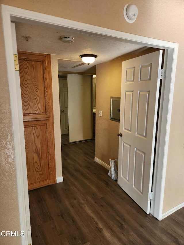 corridor featuring a textured ceiling and dark wood-type flooring