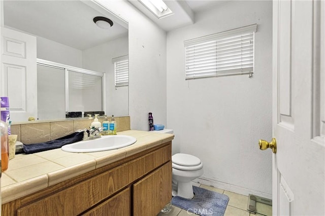 bathroom featuring toilet, vanity, tile patterned flooring, and a shower with door