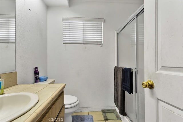 bathroom featuring tile patterned floors, vanity, toilet, and walk in shower