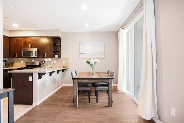 kitchen featuring kitchen peninsula, gas range oven, a kitchen breakfast bar, and dark brown cabinets