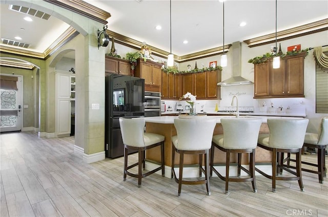 kitchen with decorative light fixtures, crown molding, and wall chimney exhaust hood