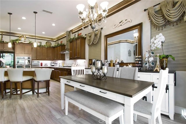 dining space featuring light wood-type flooring, an inviting chandelier, and ornamental molding