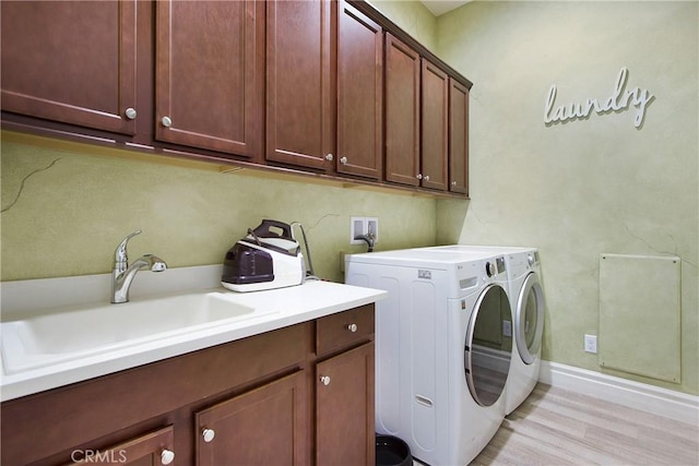 clothes washing area with cabinets, sink, independent washer and dryer, and light hardwood / wood-style floors