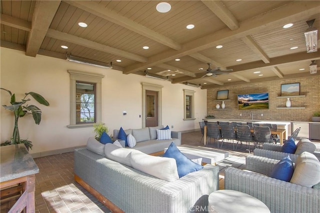 living room featuring ceiling fan, beamed ceiling, hardwood / wood-style flooring, wood ceiling, and brick wall