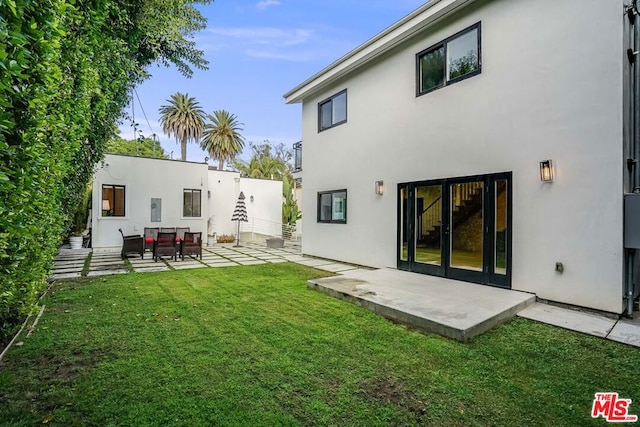 back of property with a yard and a patio area