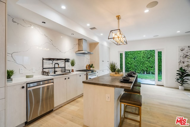 kitchen featuring dishwasher, white cabinetry, hanging light fixtures, a center island, and wall chimney exhaust hood