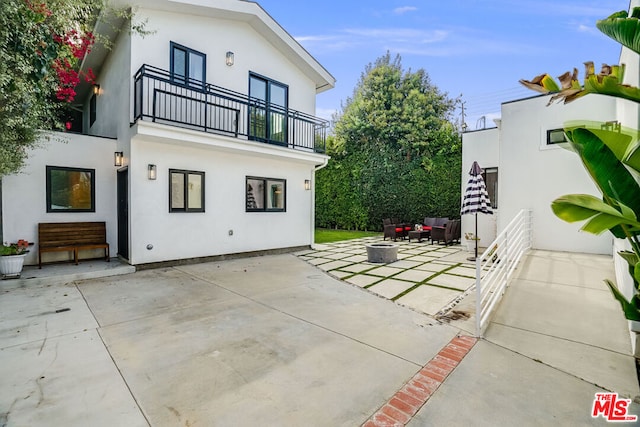 back of house with a balcony, an outdoor fire pit, and a patio area