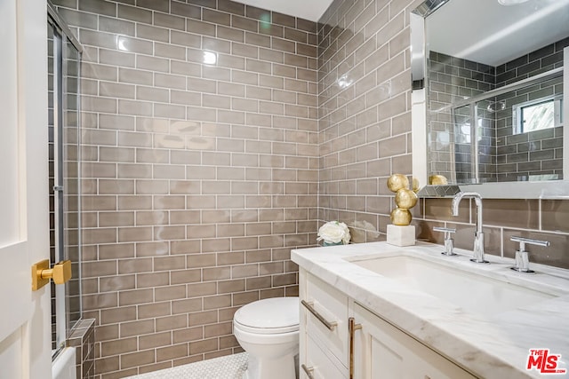 full bathroom featuring bath / shower combo with glass door, tile walls, vanity, toilet, and tile patterned floors