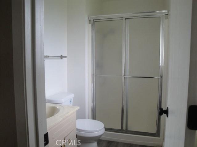 bathroom with toilet, vanity, an enclosed shower, and hardwood / wood-style flooring