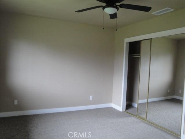 unfurnished bedroom with ceiling fan, a closet, and carpet floors