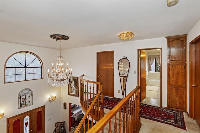 corridor with light carpet and a chandelier