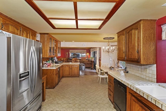 kitchen featuring decorative light fixtures, dishwasher, tile counters, stainless steel fridge, and a notable chandelier