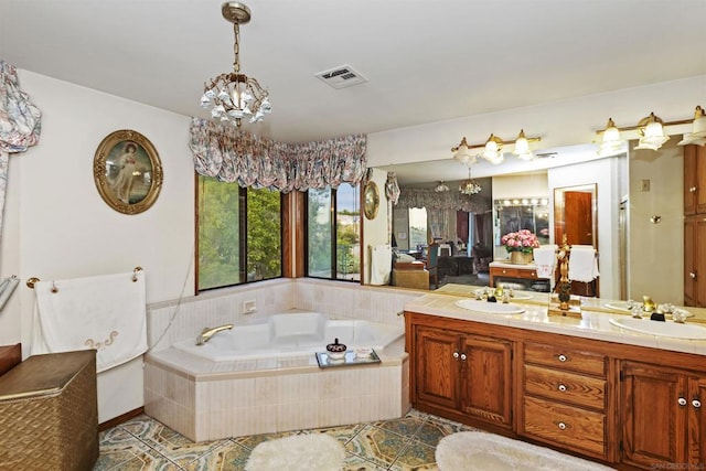 bathroom featuring tiled bath, tile patterned floors, a chandelier, and vanity