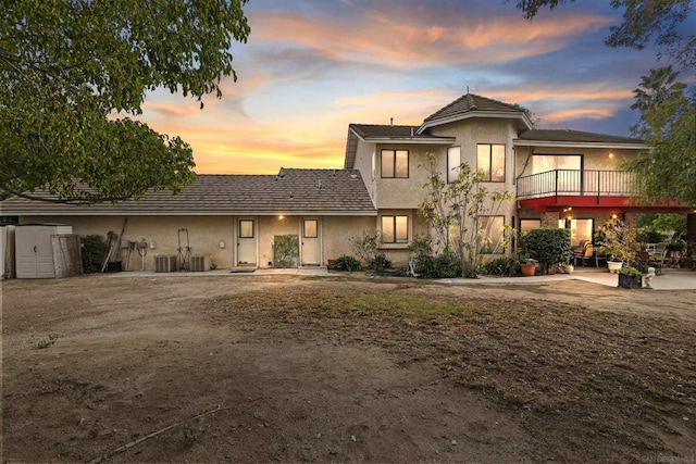 view of front of home featuring central air condition unit, a patio, and a storage shed