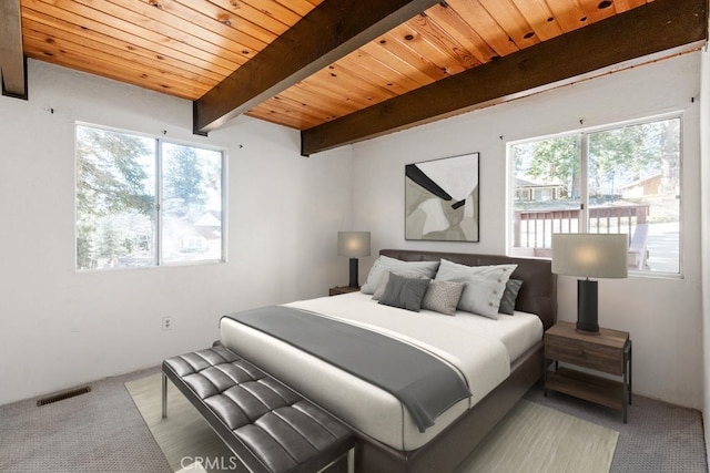 carpeted bedroom featuring beam ceiling, wood ceiling, and multiple windows